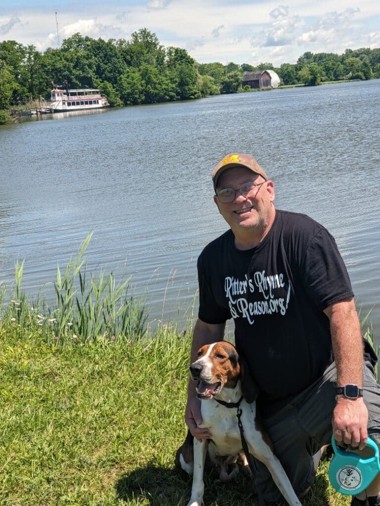 David Ritter kneeling down with his beloved dog Sonny in front of Mott Lake 2024